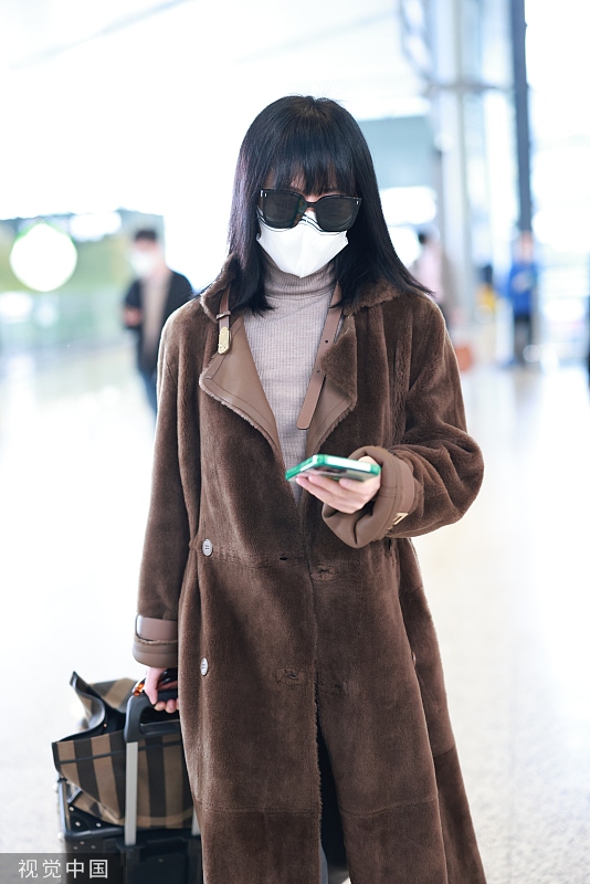 谭卓穿驼色大衣戴墨镜现身机场 专心看消息步履匆匆